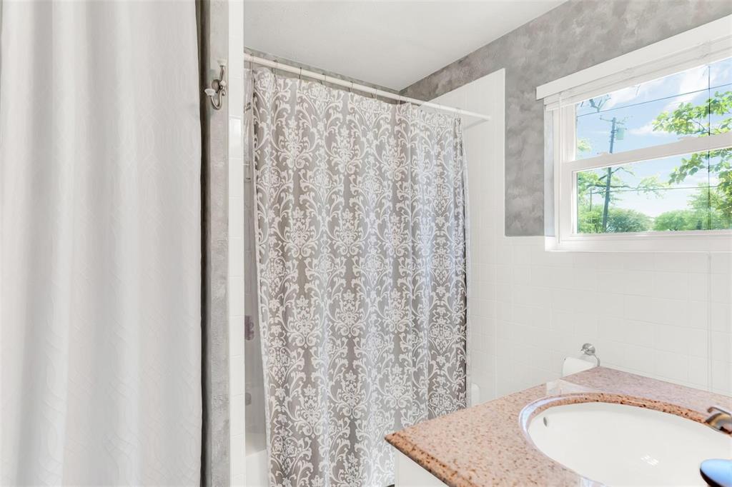 319 East Spring Valley Road Richardson, TX 75081 - Photo 14 of 22 Bathroom featuring a window, white subway tile wainscoting, a vanity with an integrated sink, and a speckled countertop