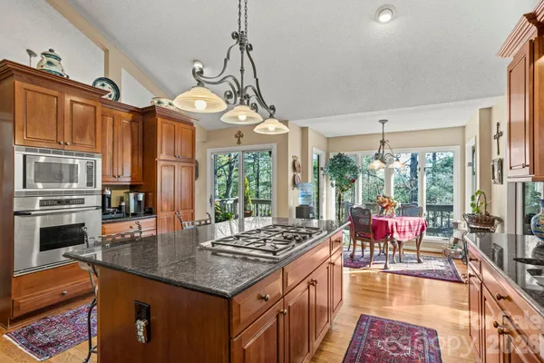 a kitchen with granite countertop a stove a sink dishwasher a dining table and chairs with wooden floor
