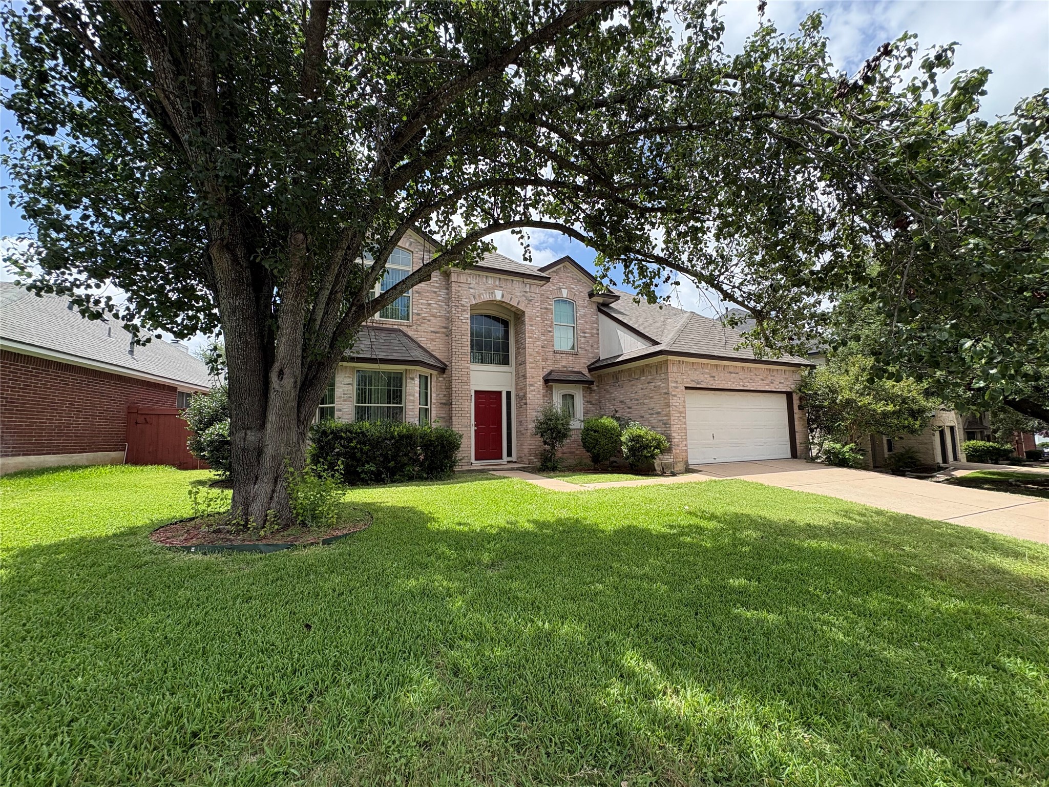 8103 Ephraim Road Austin, TX 78717 - Photo 3 of 35 A well-maintained lawn welcomes you to this brick-front home with a prominent red entry door and an attached garage.