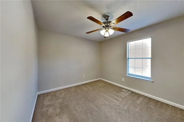 an empty room with a window and a fan