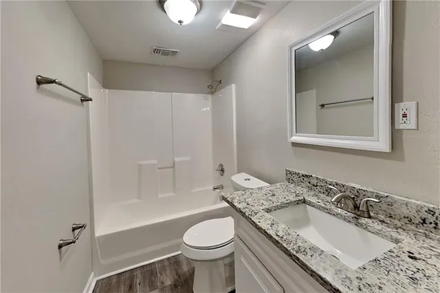 a bathroom with a granite countertop sink toilet and shower