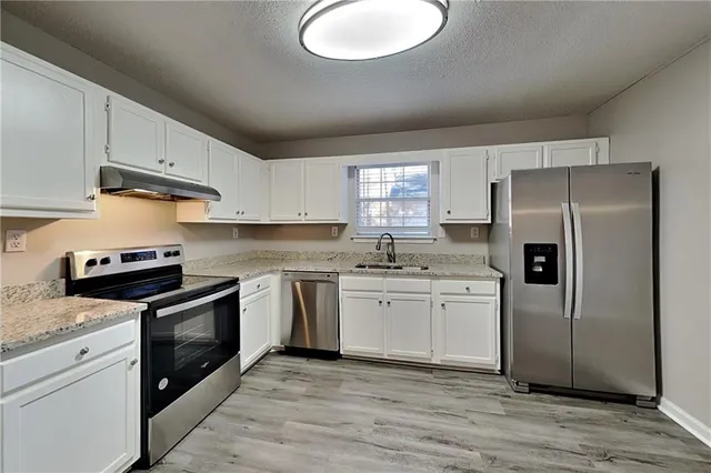 a kitchen with granite countertop white cabinets and stainless steel appliances