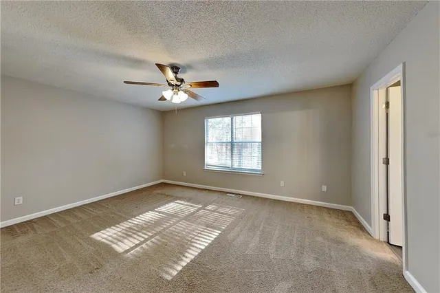 an empty room with windows and fan