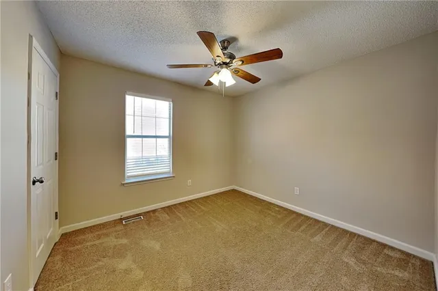 an empty room with a window and a fan