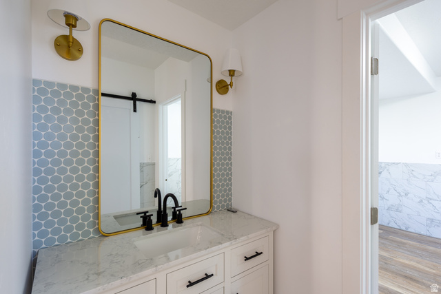 868 Braddock Lane Alpine, UT 84004 - Photo 49 of 64 Vanity featuring a gold-framed mirror, dual brass sconces, hexagon tile backsplash, and a white countertop with an integrated sink