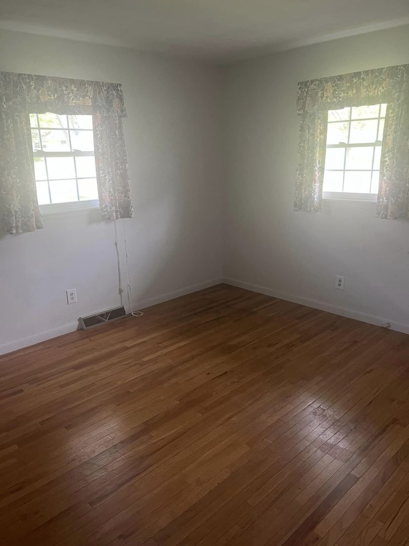 24 Brookwood Drive Normal, IL 61761 - Photo 7 of 12 an empty room with wooden floor and windows