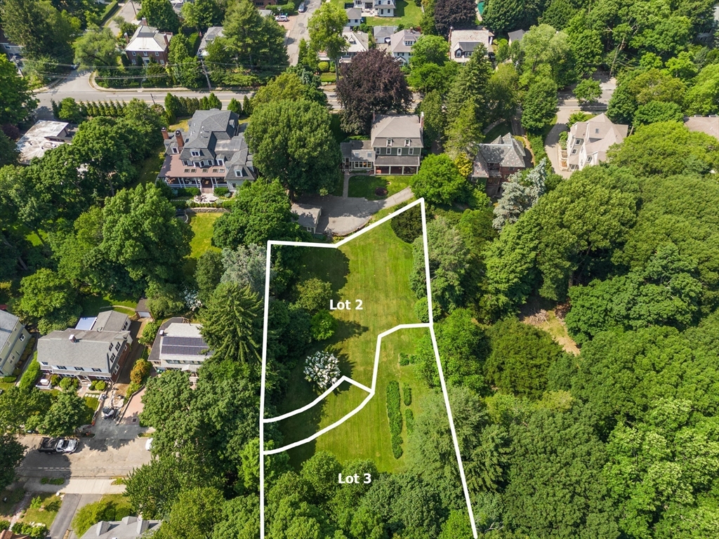 an aerial view of a residential houses with yard and trees