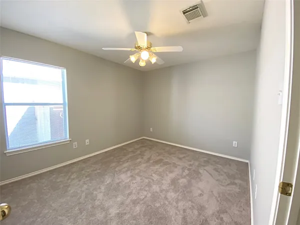 an empty room with a chandelier fan and windows
