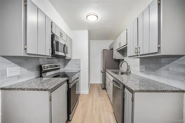 a kitchen with stainless steel appliances granite countertop a sink stove and refrigerator