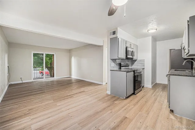 a kitchen with stainless steel appliances a stove top oven a sink dishwasher and a refrigerator with wooden floor