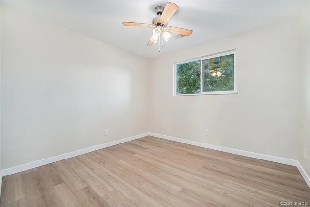 a view of a room with wooden floor and a ceiling fan