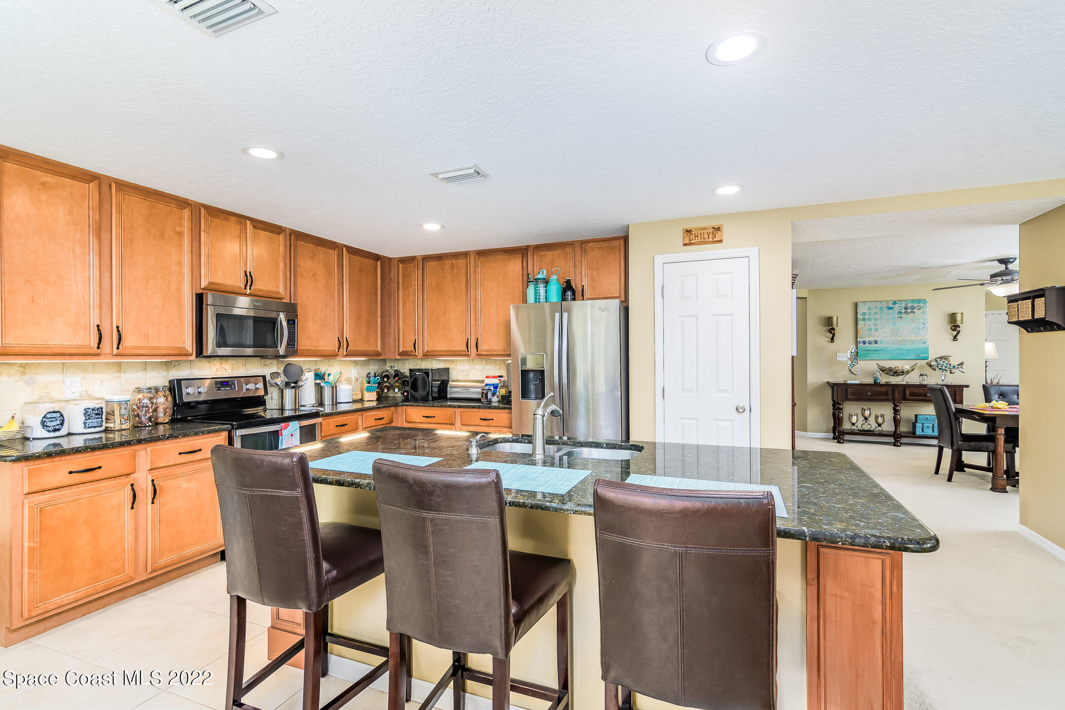 372 Franzing Street Palm Bay, FL 32908 - Photo 10 of 23 a kitchen with stainless steel appliances granite countertop a stove top oven a sink dishwasher a dining table and chairs with wooden floor