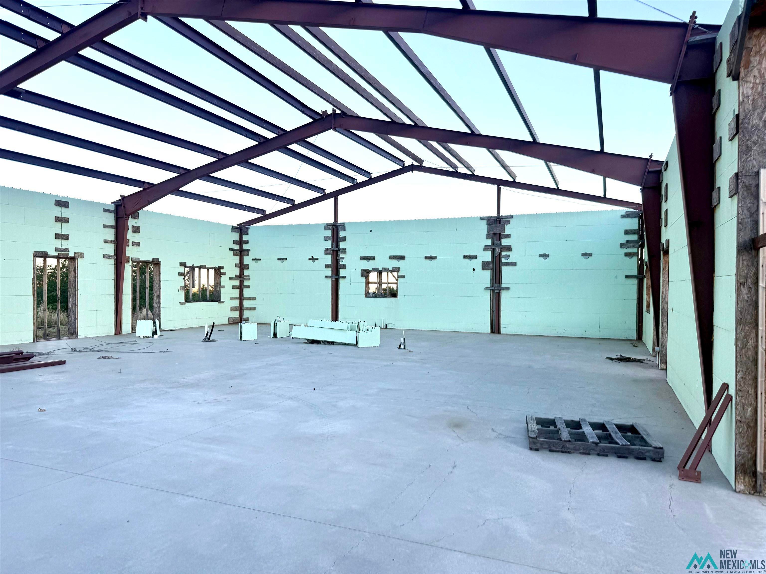 25 Linwood Road Raton, NM 87740 - Photo 9 of 41 Large unfinished interior space with a concrete floor, exposed structural steel beams, and light green insulated concrete form (ICF) walls