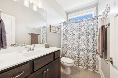a bathroom with a sink a toilet a mirror and shower curtain