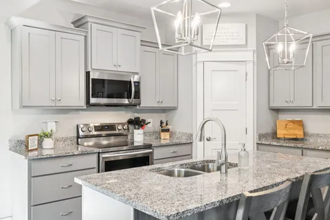 a kitchen with granite countertop a sink a stove and cabinets