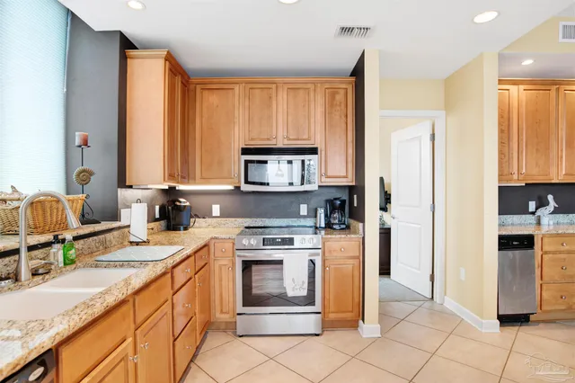 a kitchen with stainless steel appliances granite countertop a stove a sink and a refrigerator with wooden floor