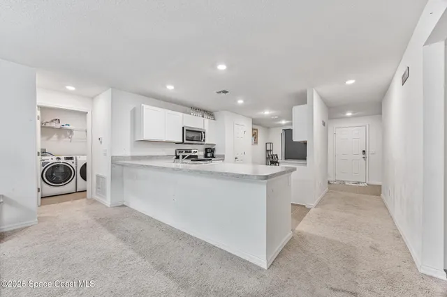 a view of kitchen with kitchen island and stainless steel appliances