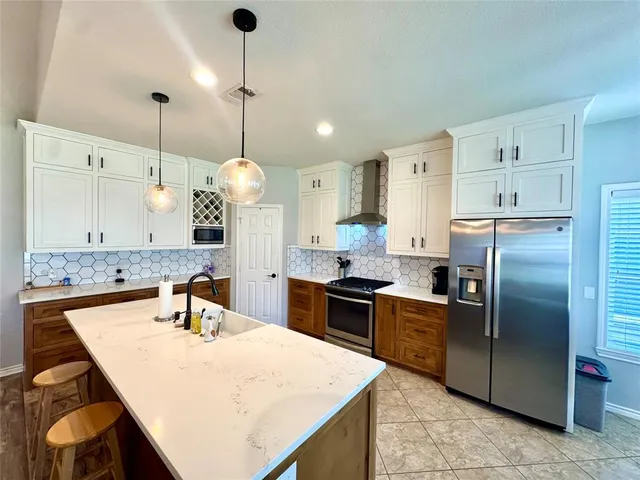a kitchen with granite countertop a sink a counter top space stainless steel appliances and cabinets