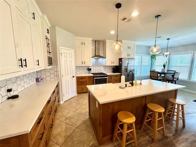 a large kitchen with kitchen island a stove a sink a center island and a wooden floor