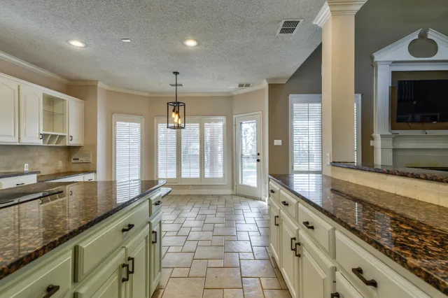 an empty room with wooden floor and a kitchen