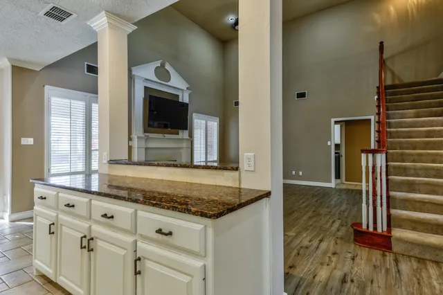a view of a hallway with wooden floor and a kitchen