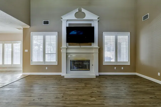 an empty room with a chandelier fan and windows