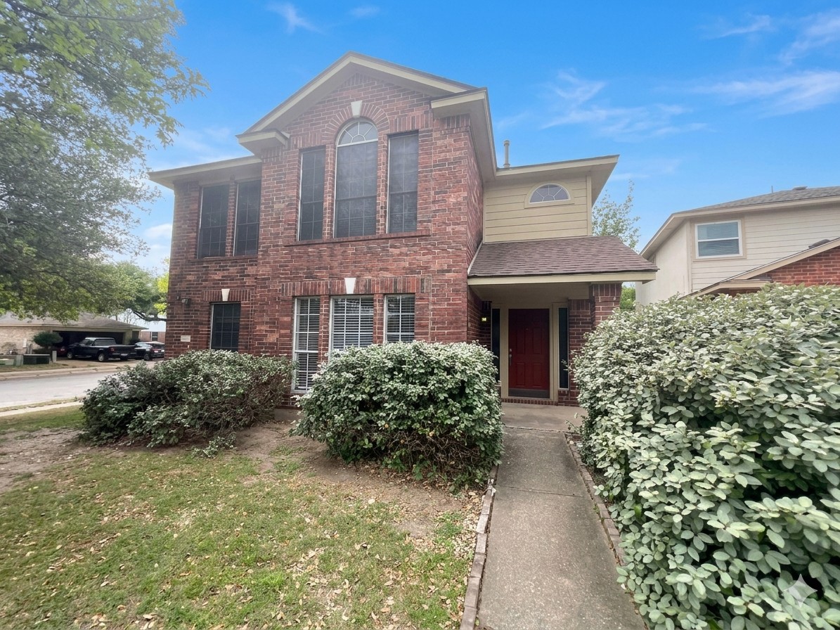Traditional-style house with brick siding and a front yard. Sky has been enhanced with the help of AI.