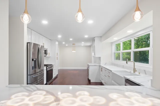a view of kitchen with stainless steel appliances granite countertop a sink a refrigerator and a stove