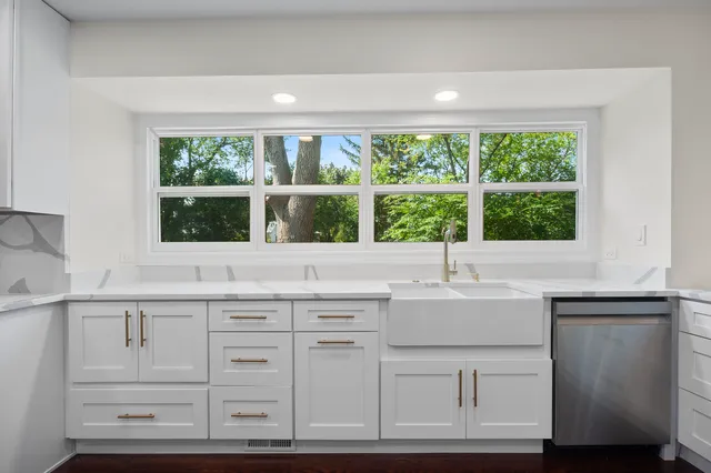 a kitchen with white cabinets and a window