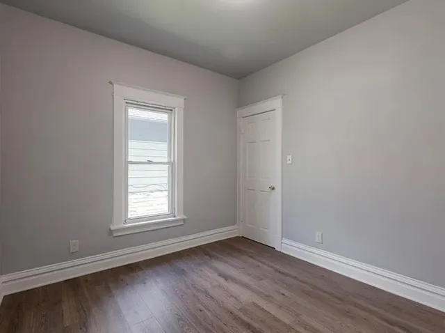 an empty room with wooden floor and window
