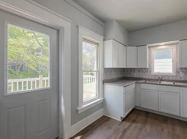 a kitchen with stainless steel appliances granite countertop white cabinets and wooden floor