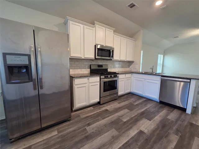 a kitchen with stainless steel appliances granite countertop a stove a sink and a refrigerator