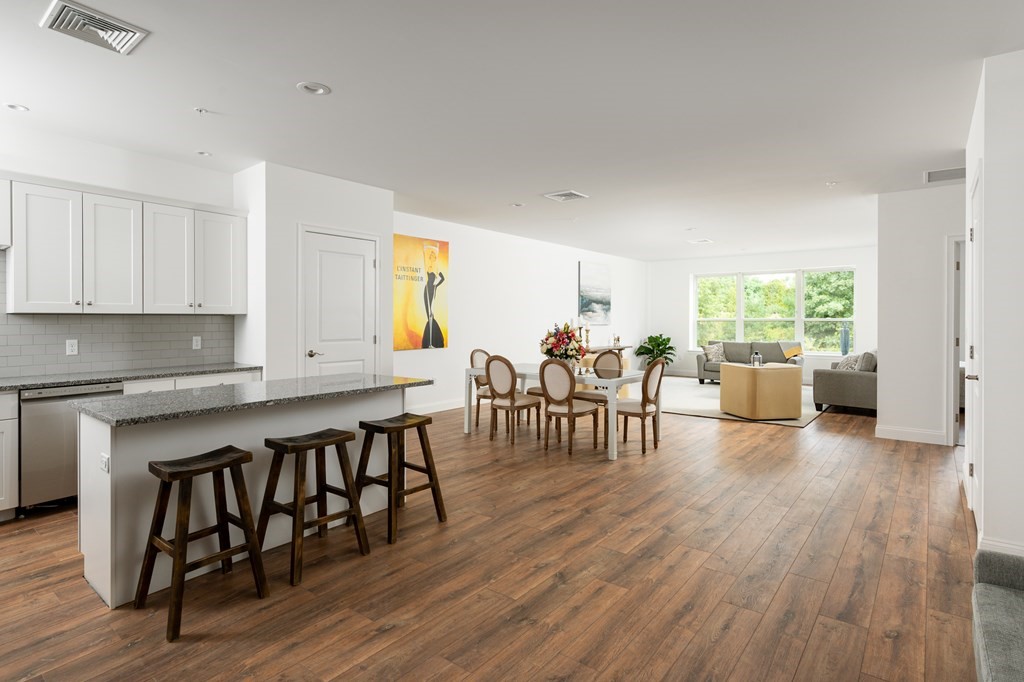 390 Chief Justice Cushing Highway, Unit 209 Cohasset, MA 02025 - Photo 1 of 16 a open kitchen with dining table chairs and wooden floor