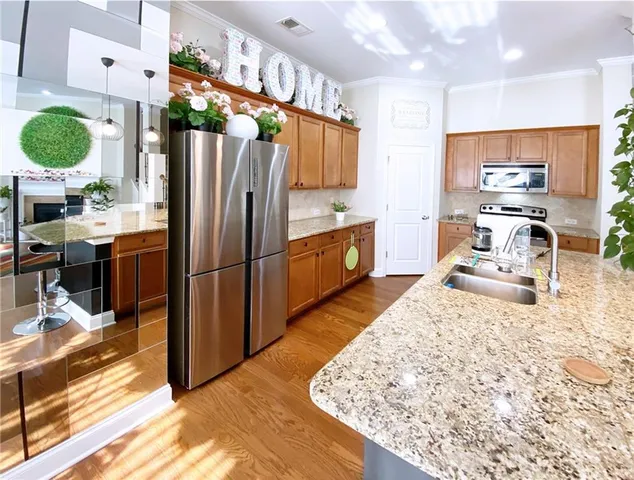 a kitchen with stainless steel appliances kitchen island granite countertop a refrigerator stove oven and white cabinets