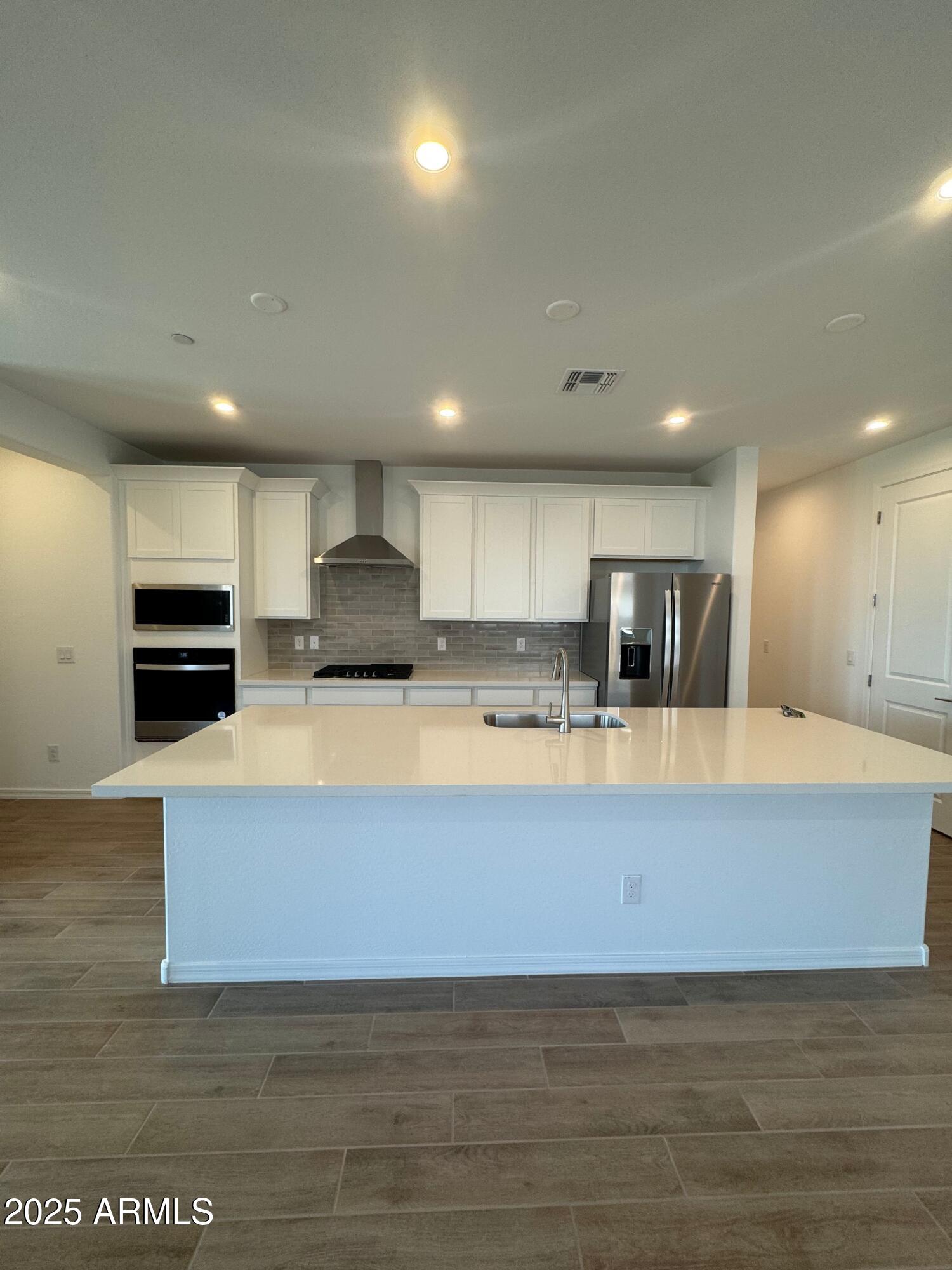 13351 West Eagle Feather Road Peoria, AZ 85383 - Photo 3 of 23 a large kitchen with stainless steel appliances a large counter top a stove and a refrigerator