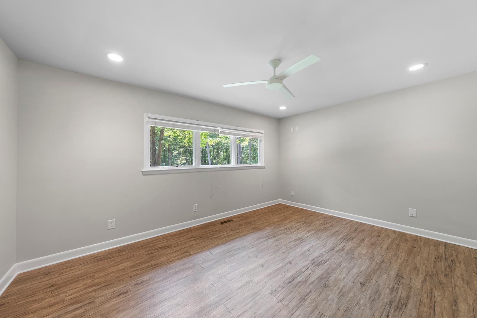 1605 Ridge Road Raleigh, NC 27607 - Photo 18 of 36 an empty room with wooden floor chandelier fan and windows