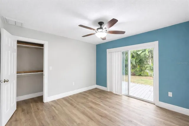a view of empty room with wooden floor and fan