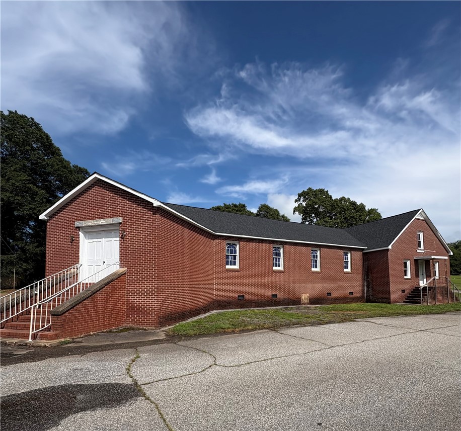 415 Church Street Pendleton, SC 29670 - Photo 1 of 35 A classic brick edifice featuring multiple windows and clean white entryways under a clear sky.