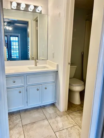 a bathroom with a granite countertop sink a toilet and a mirror