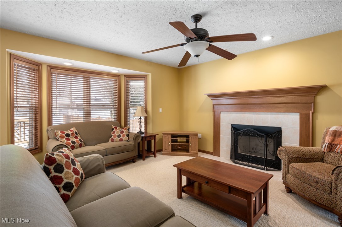 9132 Reed Road North Ridgeville, OH 44039 - Photo 8 of 43 Carpeted living area with a tiled fireplace, a textured ceiling, a ceiling fan, and recessed lighting