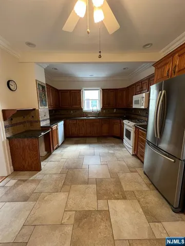 a kitchen with granite countertop a refrigerator and a stove top oven