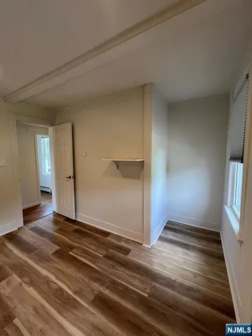 a view of an empty room with window and wooden floor