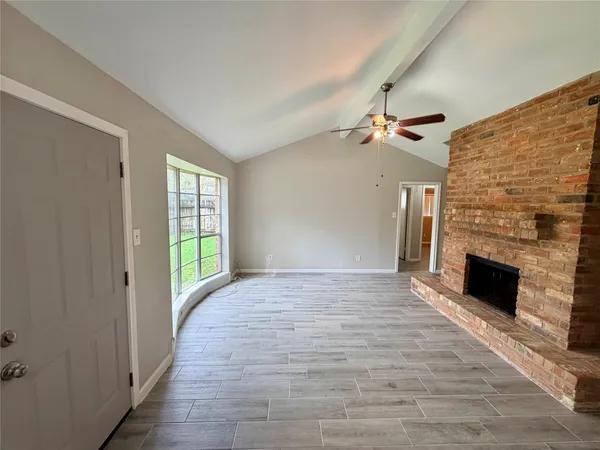 an empty room with wooden floor fan and windows