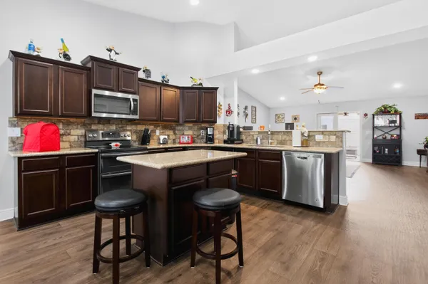 a kitchen with stainless steel appliances granite countertop a stove top oven a sink dishwasher and cabinets with wooden floor