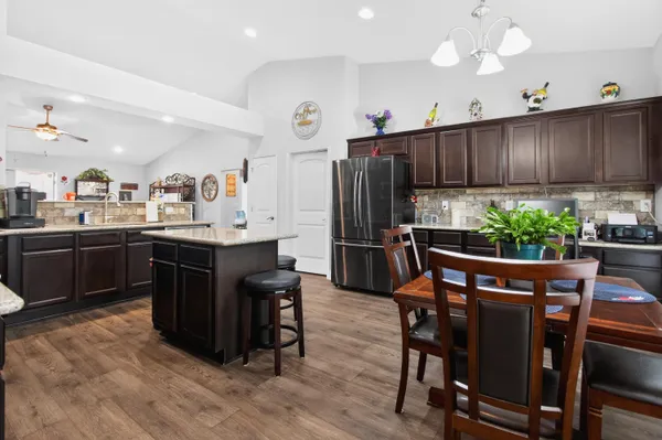 a kitchen with stainless steel appliances kitchen island granite countertop a table chairs sink and cabinets