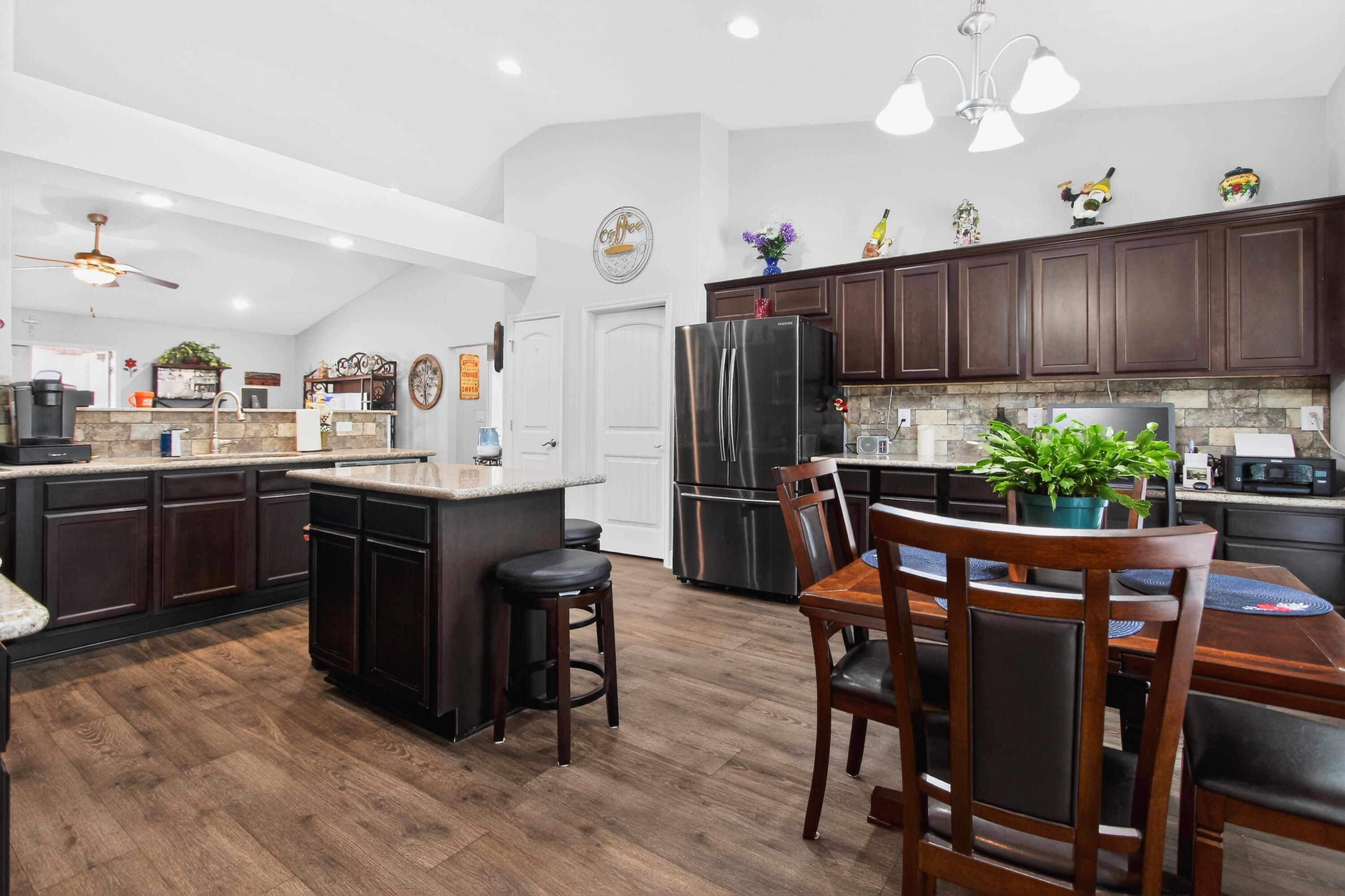 6317 Antigone Circle Crestview, FL 32536 - Photo 8 of 32 a kitchen with stainless steel appliances kitchen island granite countertop a table chairs sink and cabinets