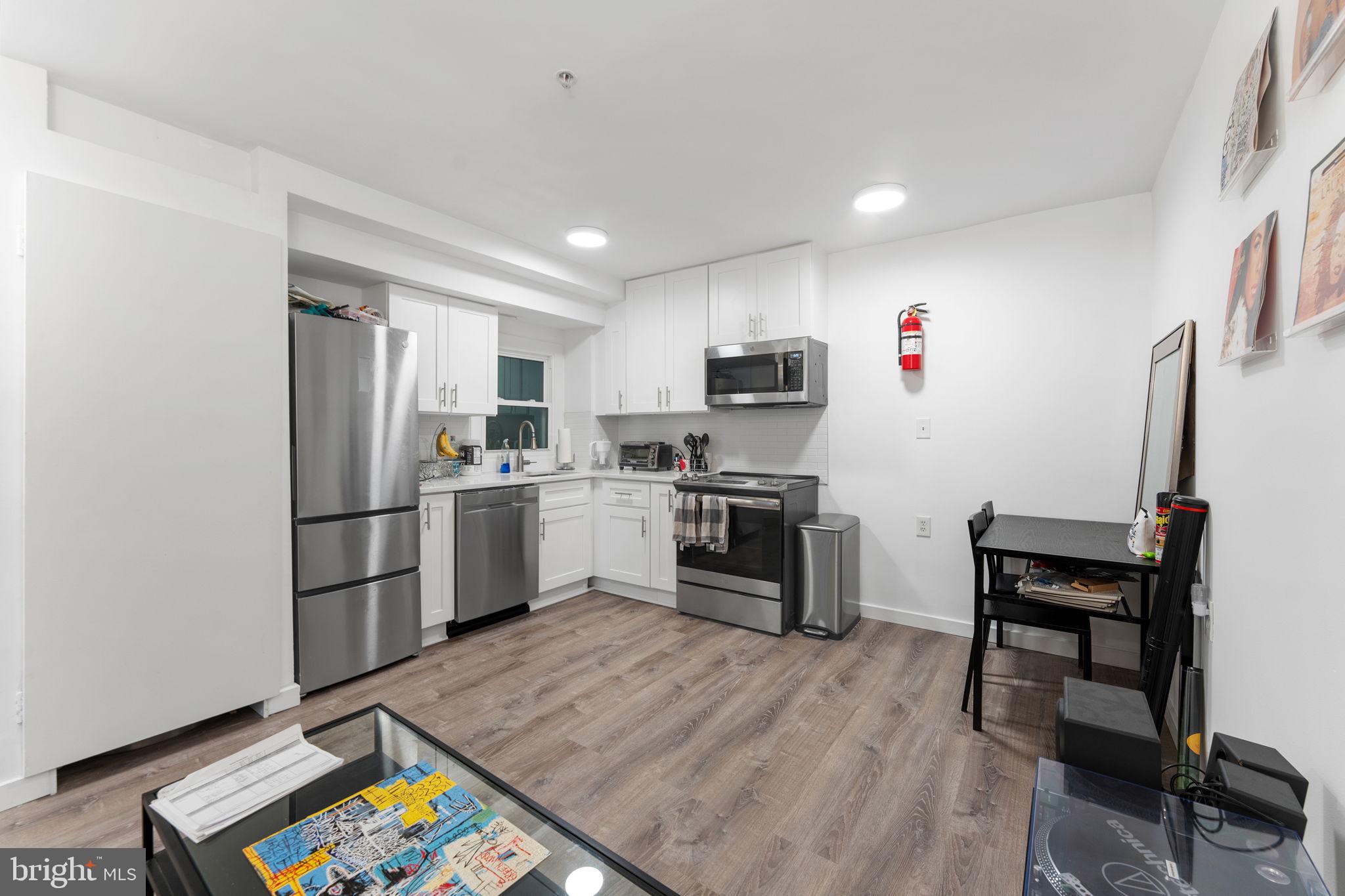 1119 6th Street Northwest, Unit 3 Washington, DC 20001 - Photo 4 of 9 a kitchen with a refrigerator a stove top oven a sink dishwasher and white cabinets with wooden floor