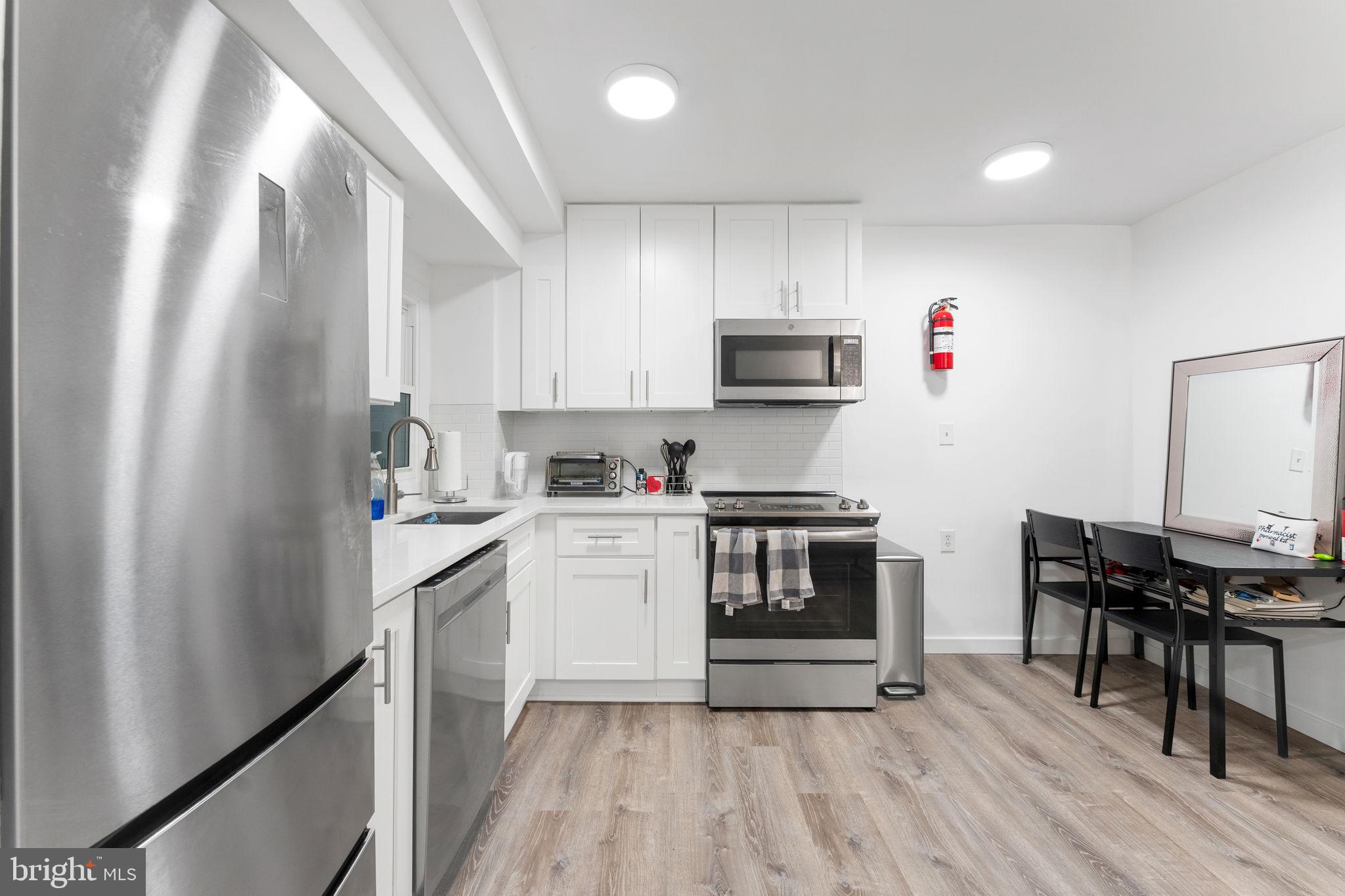 1119 6th Street Northwest, Unit 3 Washington, DC 20001 - Photo 5 of 9 a kitchen with stainless steel appliances a stove a sink dishwasher and a refrigerator with wooden floor
