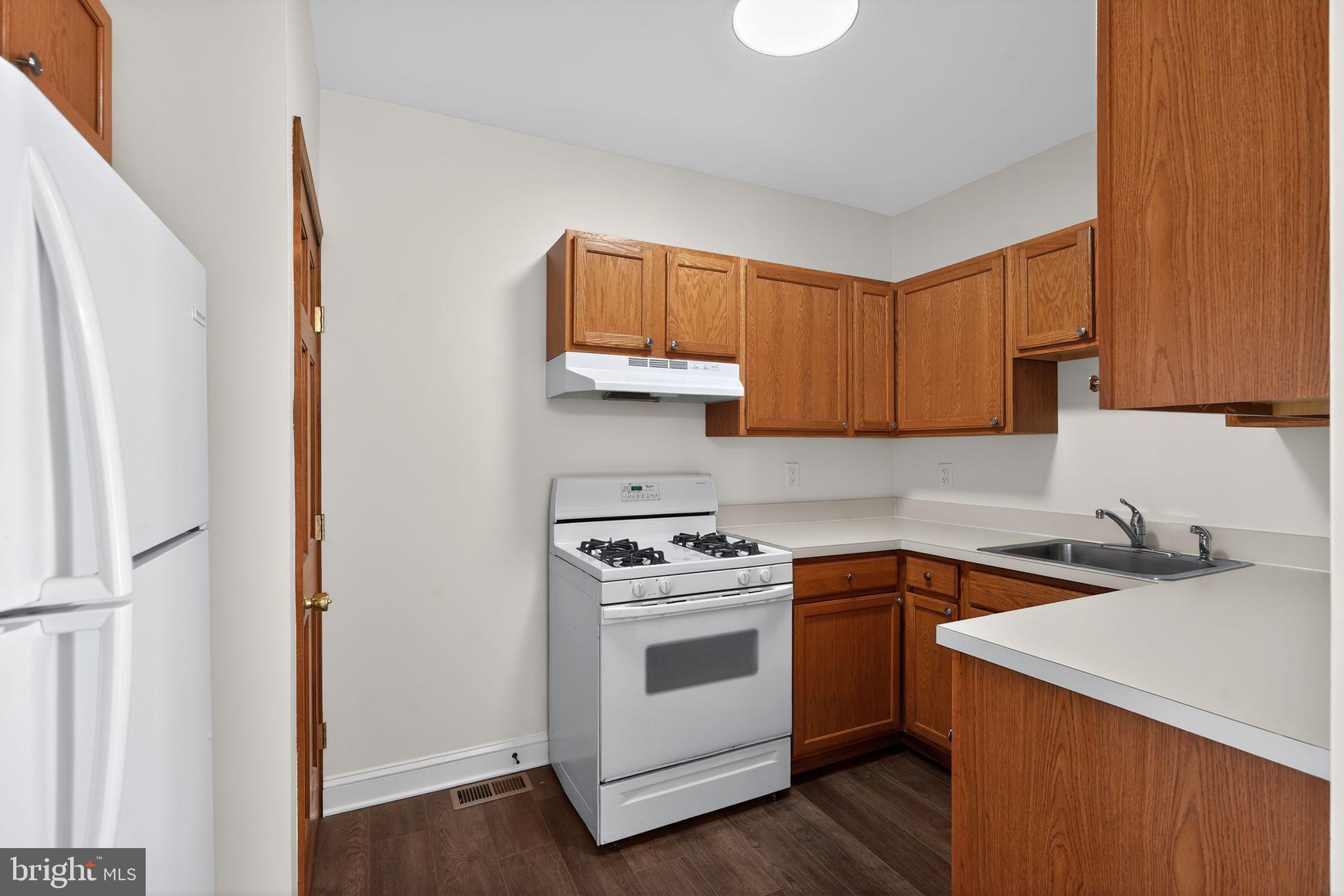511 3rd Avenue Audubon, NJ 08106 - Photo 11 of 23 a kitchen with a sink dishwasher a stove and a refrigerator with wooden floor