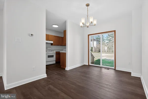 a view of a hallway with wooden floor and a kitchen